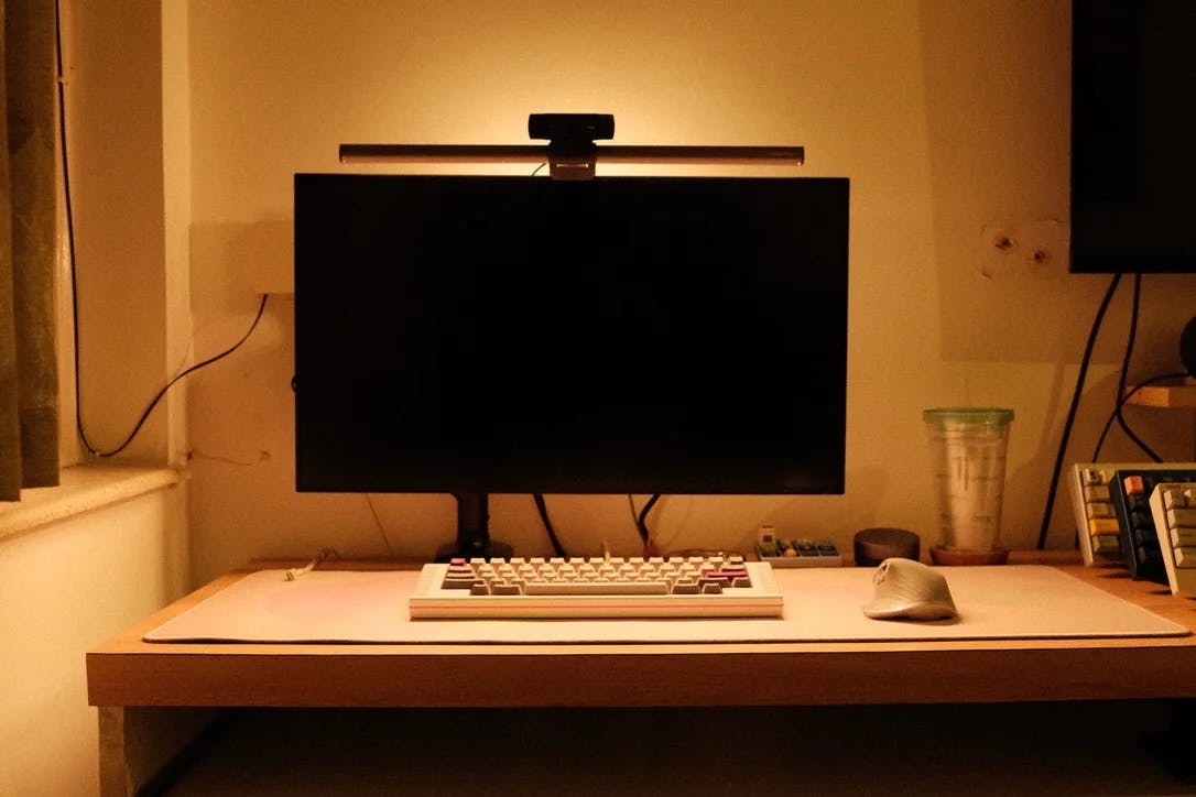An external monitor, mechanical keyboard, and mouse under warm lighting.