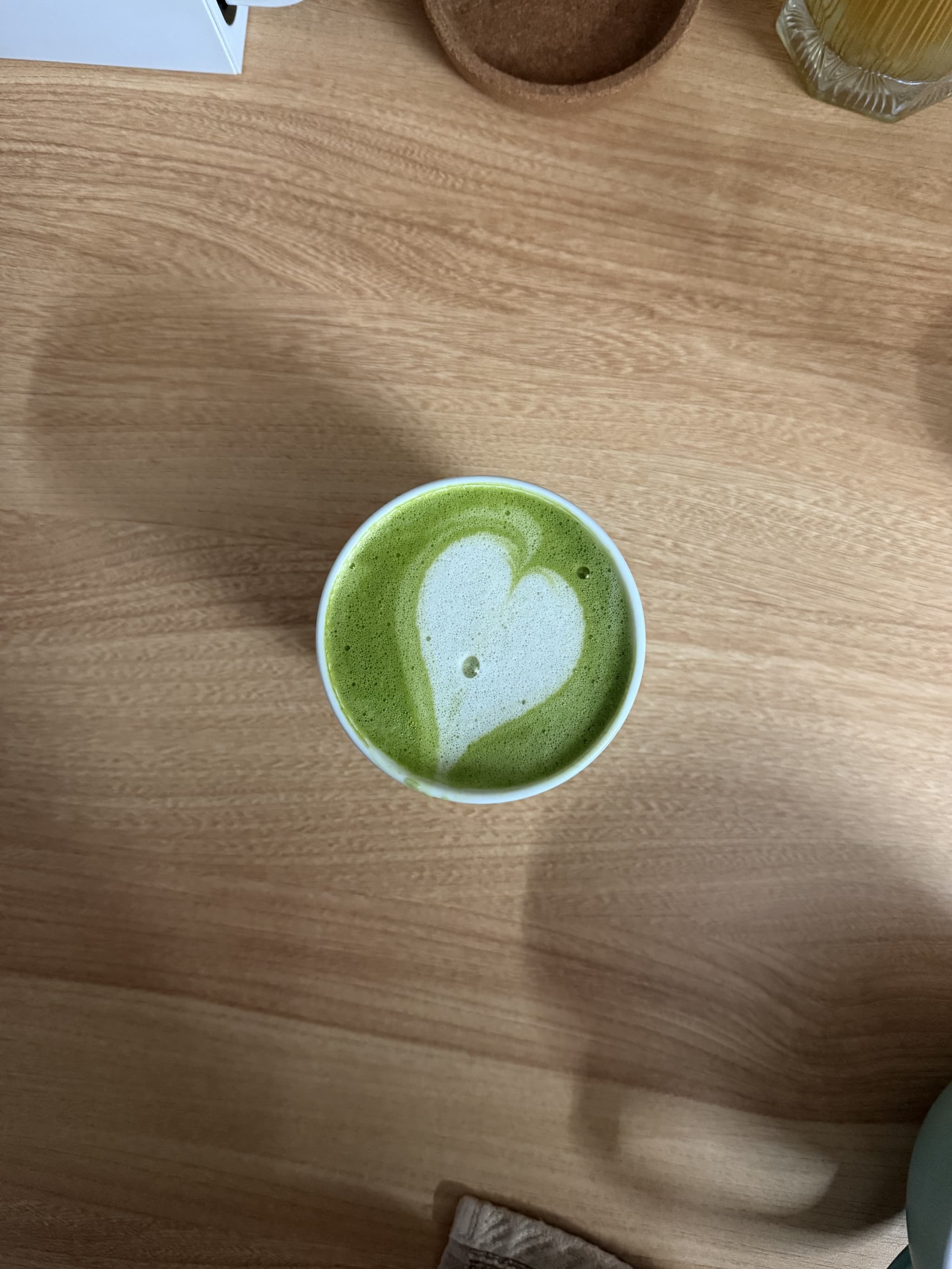 A heart-shaped latte art on a matcha latte