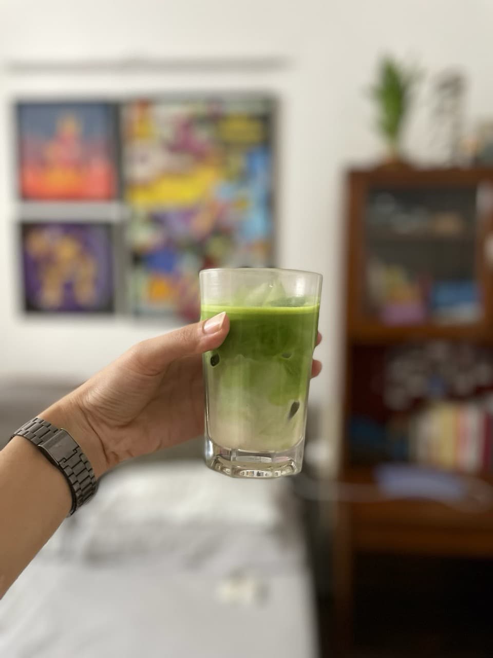 A glass of milk and ice topped with freshly prepared matcha tea.