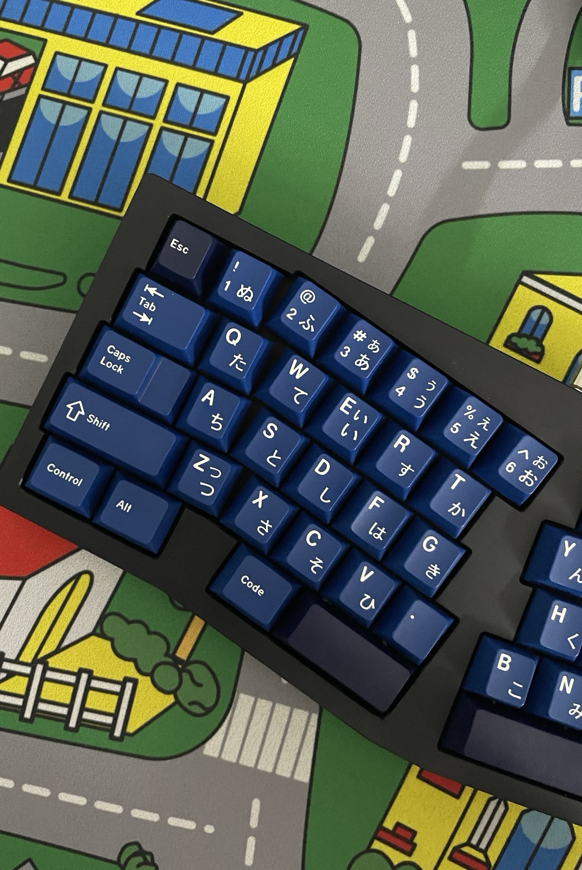 Photo of a alice style, ergonomic keyboard with a navy blue keycap set with japanese sub-legends.