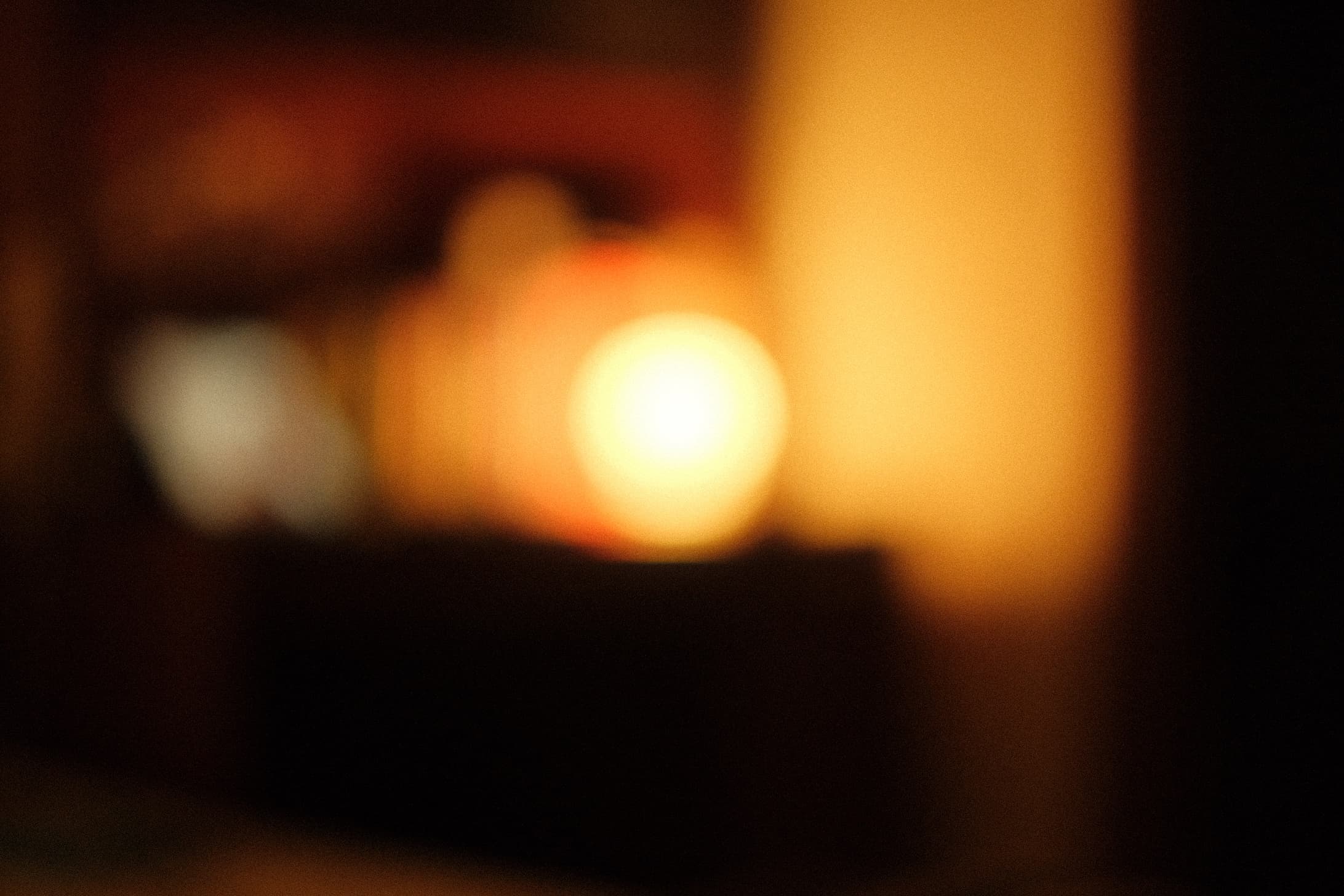 Blurred warm light source glowing in darkness with orange and golden tones