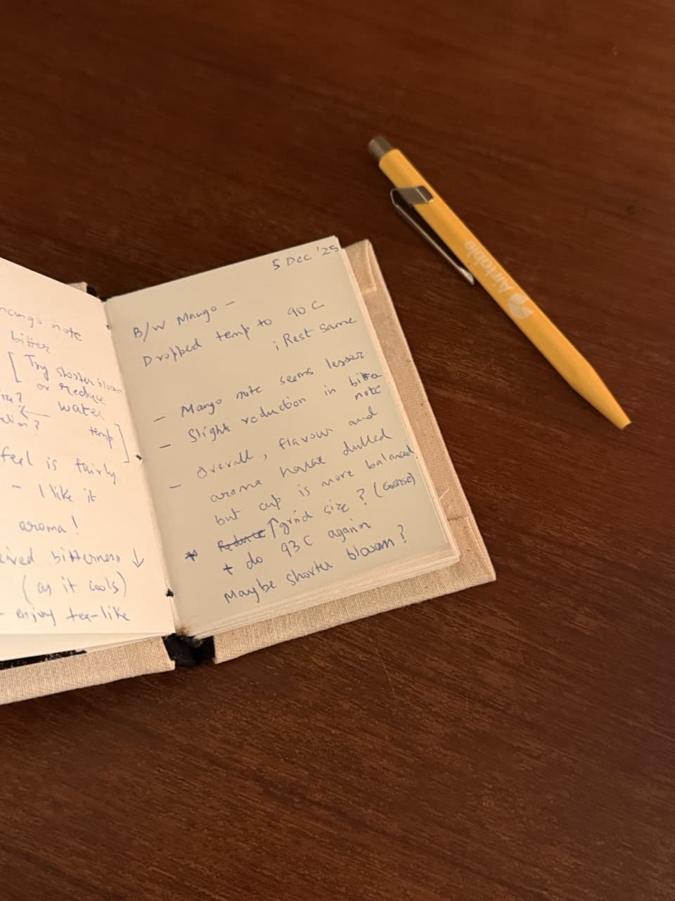 Open coffee diary notebook with handwritten tasting notes dated 5 Dec 2025 and yellow pen on wooden surface