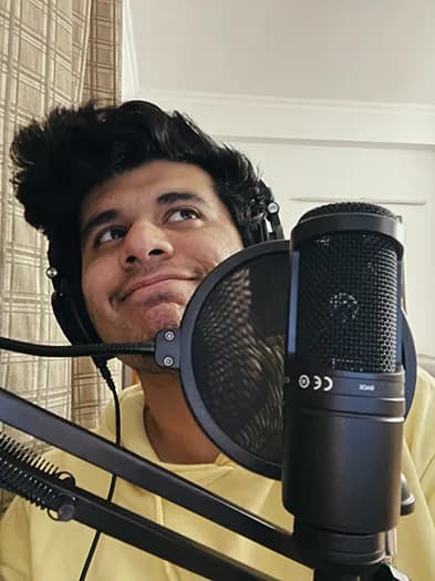 Ratik in front of a podcasting mic